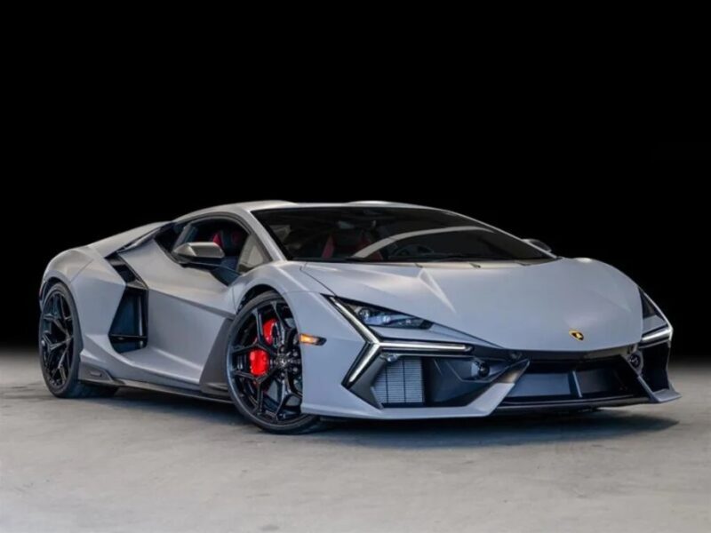 A sleek, matte gray Lamborghini Revuelto sports car with an angular design is visible from a low angle against a dark background.