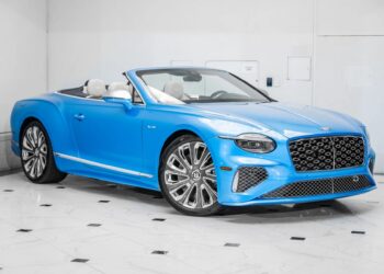 A blue Bentley Continental GTC convertible with its top down is parked indoors on a white tiled floor, showcasing the elegance of this luxury tourer.