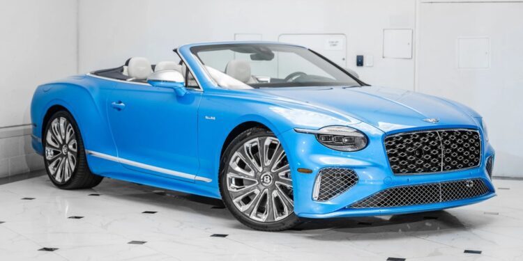 A blue Bentley Continental GTC convertible with its top down is parked indoors on a white tiled floor, showcasing the elegance of this luxury tourer.