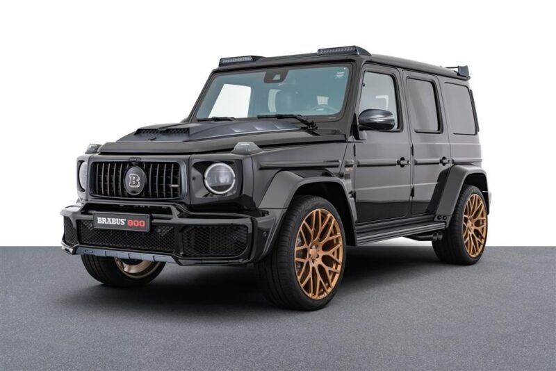 A unique creation, this black SUV with bronze alloy wheels and a Brabus 800 badge on the front bumper stands proudly on a gray surface against a white background. Perfect for enthusiasts who value custom cars nurtured in the finest garages.