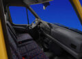 Interior of a 30th Anniversary Mercedes-Benz Sprinter with a striking yellow exterior showcases a sleek steering wheel, manual gear shift, and patterned seats. The elegant design is set against a solid blue background.