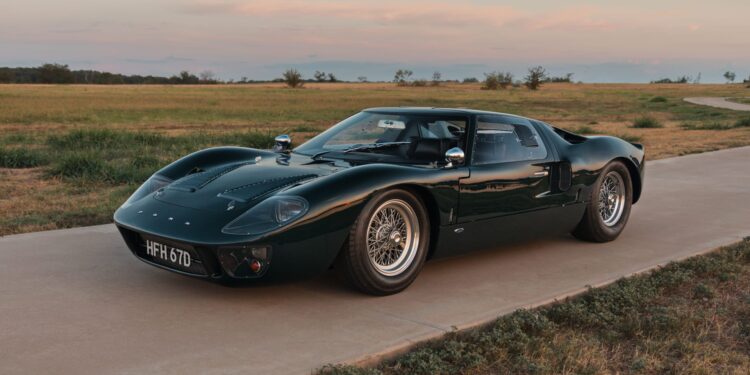A classic dark green sports car, reminiscent of the elegant machines often seen at Mecum Auctions in Kissimmee 2025, is parked on a paved road. The scene is framed by grassy fields under a cloudy sky, evoking the allure of expensive cars amidst nature's tranquility.