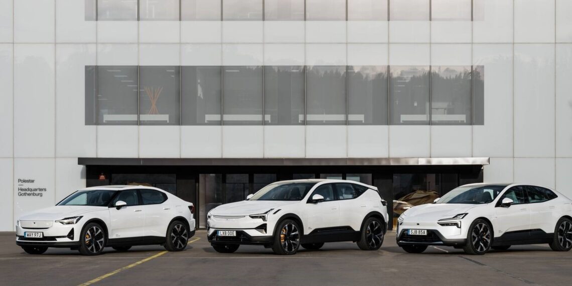 Three white electric cars are parked in front of a modern building with large glass windows.