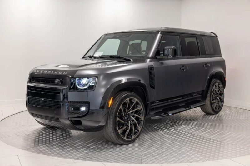 In a pristine showroom, a matte black SUV dazzles as a unique creation with its modern design, large wheels, and sleek body—a true testament to the art of custom cars.