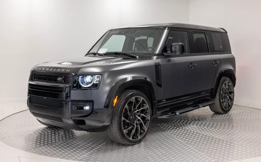 In a pristine showroom, a matte black SUV dazzles as a unique creation with its modern design, large wheels, and sleek body—a true testament to the art of custom cars.