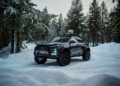 A rugged, modified Audi Q6 e-tron concept with large tires and roof rack is parked in a snowy forest setting, ready for offroad adventures.