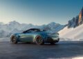 A Vantage Roadster is parked on a snowy mountain road, boasting a scenic backdrop of snow-covered peaks under a clear blue sky.