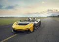 A yellow and black Automobili Pininfarina sports car, a groundbreaking 2024 marvel, stands elegantly on an empty road with a scenic mountain backdrop under a cloudy sky.