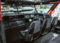 Interior view of a luxury boat cockpit featuring three Black Ops Signature Edition black upholstered seats, a steering wheel, and multiple digital displays on a sleek BRABUS control panel.