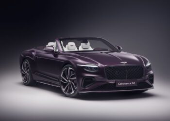 A sleek, purple Bespoke Bentley convertible sports car with the top down showcases a luxurious interior against a dark background, reminiscent of the elegance found in a $1.7M auction masterpiece.