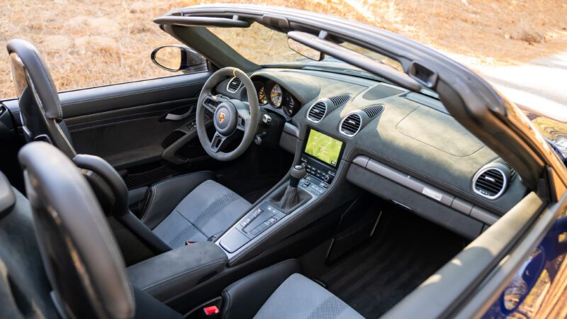 Interior view of a convertible sports car featuring a touchscreen display, leather seats, and a steering wheel.