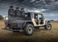 A WARHAWK-modified off-road vehicle, outfitted by Hennessey Defense Systems, stands boldly on grassy terrain with open doors and rear-mounted seats, all beneath an overcast sky.