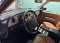 The interior of this rare vintage car exudes luxury with its wood-accented dashboard, plush leather seats, and a steering wheel adorned with an emblem. Reminiscent of the Bentley Turbo RT, the dashboard boasts various dials and controls for an exquisite driving experience.