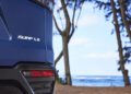 A close-up of the rear of a blue Surf LX Concept SUV, labeled "SURF LX," parked near a beach. With trees swaying gently and the ocean stretching out in the background, it’s easy to imagine cruising through Hawaii in style.