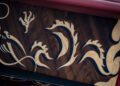 Intricate wood inlay design featuring abstract floral patterns with light and dark wood tones, framed by red leather upholstery, reminiscent of a Phantom Dragon's elegance in every bespoke detail.