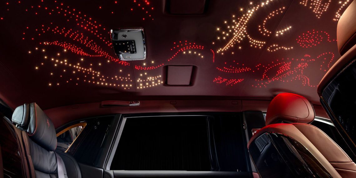 Experience the bespoke luxury of a Rolls-Royce interior, where an illuminated ceiling dazzles with star-like and abstract patterns in red and white, creating an ethereal ambiance.