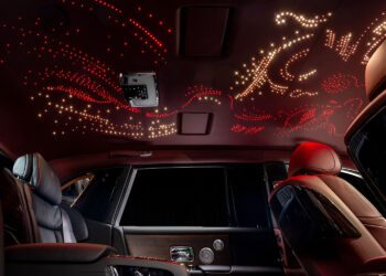 Experience the bespoke luxury of a Rolls-Royce interior, where an illuminated ceiling dazzles with star-like and abstract patterns in red and white, creating an ethereal ambiance.