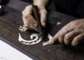 Hands crafting intricate, bespoke designs on wood with carving tools, reminiscent of a Phantom Dragon's elegance.