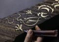 Hand carving a bespoke dragon design into dark wood with a chisel, featuring intricate curls and textured patterns reminiscent of the luxury found in a Rolls-Royce Phantom.