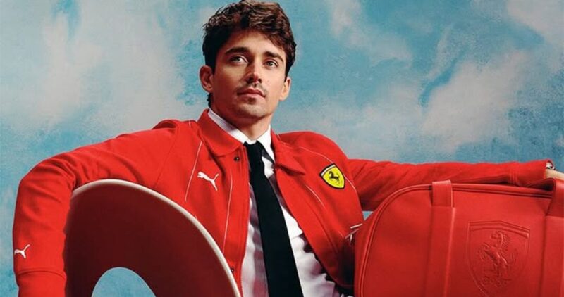 A person wearing a red Ferrari jacket sits on a chair next to a red Ferrari bag, embodying a luxurious lifestyle.