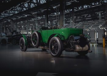 A vintage green Bentley, reminiscent of the classic Speed Six, is parked indoors. It proudly showcases its timeless design with large wheels and exposed mechanical components, echoing an era of elegance and performance.