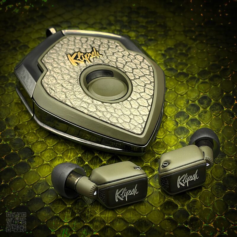 Upgrade your style with these green Klipsch earphones, perfectly nestled in a hexagonal carrying case on a textured surface. A true luxury accessory, these earphones are now for sale, combining elegance and superior sound quality.