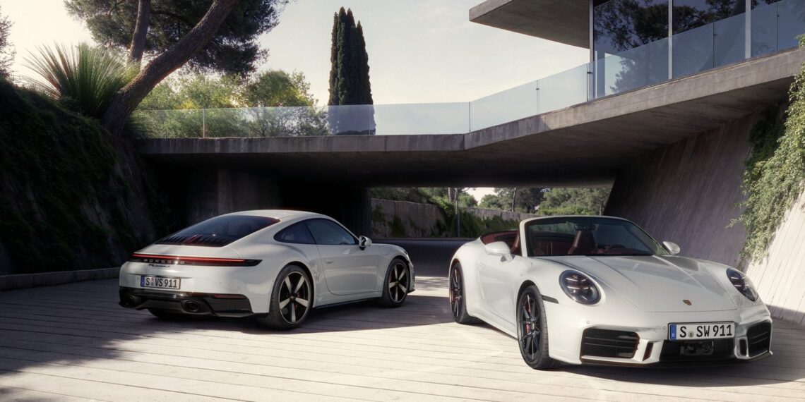 Two white sports cars parked outdoors on a sunny day, near a modern building with large windows and surrounded by trees.