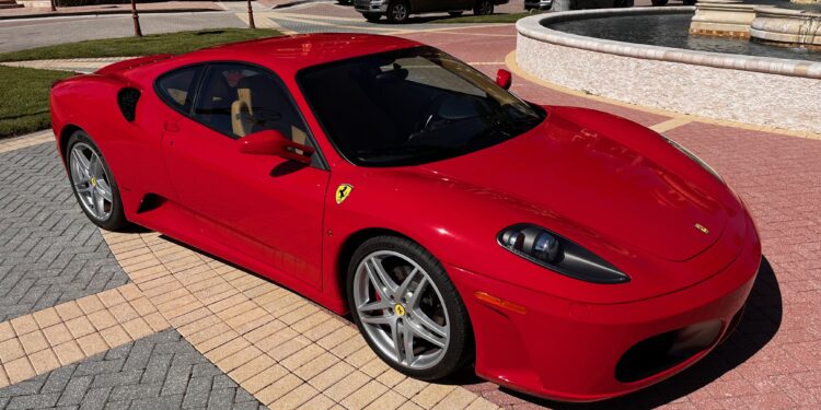 A sleek 2007 Ferrari F430 sits regally on the patterned pavement, framed by elegant buildings and a shimmering fountain, exuding an air of presidential provenance.