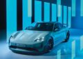 A sleek, modern Porsche Taycan Turbo GT is parked indoors with a futuristic blue and teal light display in the background, showcasing its status as the most powerful model.