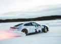 A Porsche Taycan drifts on an icy track, surrounded by snow, with motion blur enhancing its speed, vying for a potential Guinness World Record in ice drifting.