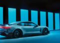 A sleek Porsche Taycan Turbo GT is parked in a futuristic setting, its powerful model silhouette highlighted by vertical blue lights illuminating the background.