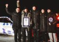 Five people celebrate next to a Porsche Taycan in a snowy environment at night, clutching a Guinness World Record certificate.