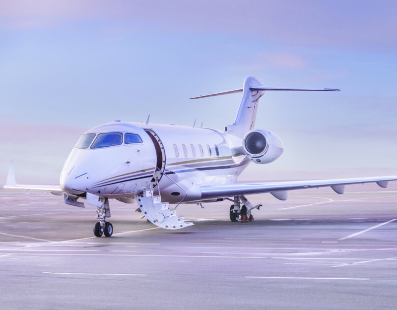 A private jet, featured in the 2025 duPont REGISTRY, sits elegantly on the airport runway with stairs deployed, inviting you to step into a world of luxury.