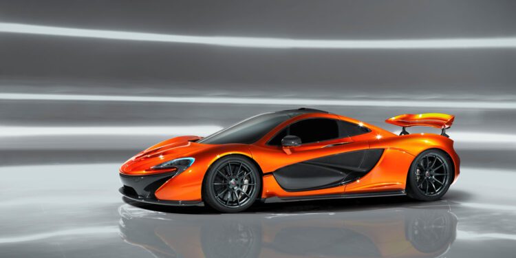 A sleek, orange McLaren P1 sports car with a prominent rear spoiler is showcased against a reflective gray background.