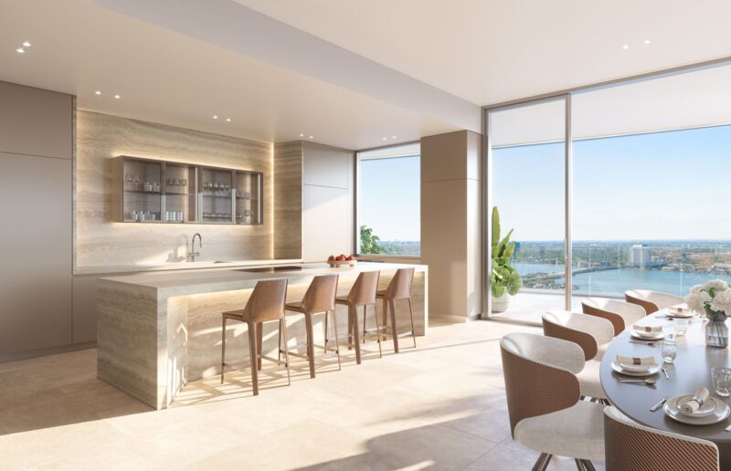 Experience a luxury kitchen at Pagani Residences, featuring a sleek stone island, bar stools, and dining area. The large windows provide a panoramic city and water view, while its neutral palette and minimalist design enhance the sophisticated ambiance.