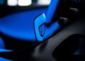 Close-up of a blue car gear shift with a small metallic emblem in the center, surrounded by black interior details, as Bugatti unveils the W16 Mistral's exquisite craftsmanship.