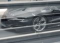 A sleek, gray Bugatti sports car viewed through horizontal glass panes, showcasing its impeccable aerodynamics.