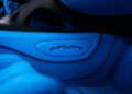 Close-up of a car interior unveils a stylized logo of a running horse on a blue panel, surrounded by overlapping blue and black surfaces reminiscent of the Bugatti W16 Mistral's elegance.