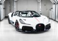 A white Bugatti sports car with a convertible top is unveiled in a brightly lit showroom, showcasing the elegance of the W16 Mistral.