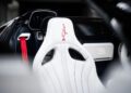 The luxury car interior unveils a white leather seat with an embossed logo and red harness seatbelt, exemplifying the elegance synonymous with Bugatti's W16 Mistral design.