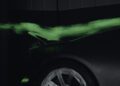 A sleek Bugatti sits in a wind tunnel, green smoke swirling to reveal the precision of its aerodynamic design as it flows effortlessly over the rear spoiler.