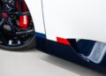 Bugatti unveils a striking close-up of the W16 Mistral's side panel, showcasing a black wheel with a red brake caliper. The panel is adorned with sleek white, blue, and red stripes, epitomizing the brand's signature elegance.