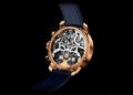 A luxury wristwatch with a gold frame and blue strap, exuding haute horology through its intricate skeleton design that reveals the gears and mechanisms beneath.