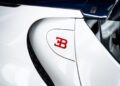 Close-up of a white car featuring a red Bugatti emblem and a curved design detail, capturing the elegance reminiscent of the Bugatti W16 Mistral.