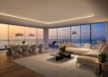 Modern living room with floor-to-ceiling windows in Tower 2, showcasing a sea view at sunset. Features a large sectional sofa, coffee table, dining area with eight chairs, and contemporary lighting—a luxurious touch in Miami real estate.