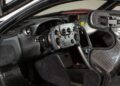 Interior of a McLaren P1 GTR boasting a carbon fiber steering wheel, digital dashboard, and bucket seat with harness, designed exclusively for track-only hypercars.