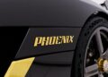 Close-up of a black vehicle with "PHOENIX" in gold letters on the side near the wheel.