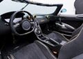 The interior of the 2018 Koenigsegg Agera RS sports convertible boasts black leather seats with yellow stitching, a central console packed with controls, and a steering wheel featuring a digital dashboard display—a true luxury experience in the heart of Phoenix.