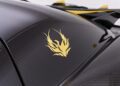 Close-up of a black carbon fiber surface with a gold phoenix decal, reminiscent of the Koenigsegg Agera RS.