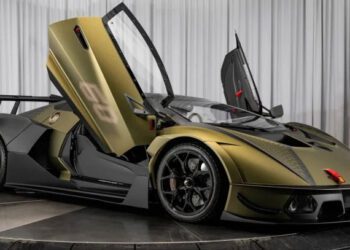 A green Lamborghini Essenza SCV12 with open scissor doors is showcased in a showroom setting, highlighting its sleek race car design, black wheels, and aerodynamic details.